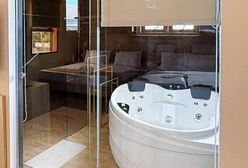 a white bath tub in a bathroom with a glass wall at RedDoorz Plus at Nick Hotel Guimba in Guimba