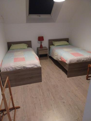 a bedroom with two beds and a tv on the wall at Cenina in Saint-Pair-sur-Mer