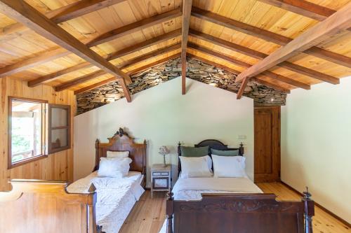 two beds in a room with wooden ceilings at Quinta da Rabaçosa - Turismo Rural in Castro Daire