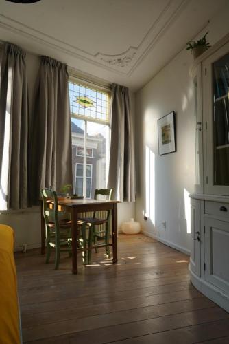 a dining room with a table and chairs and a window at De Verwondering Privé etage met 2 slaapkamers in Gouda