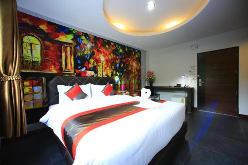 a bedroom with a large white bed with a painting on the wall at D11 Hotel in Phitsanulok