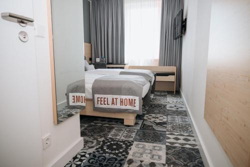 a bedroom with two beds and a sign that reads feel at home at Coffee Fellows Hotel München-Freiham in Munich