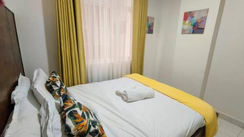a small bedroom with a bed with a yellow curtain at Kiambu road Green Zone Macedonia in Kiambu
