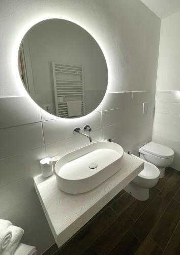 a white bathroom with a sink and a mirror at Ginevra Boutique Rooms - Palazzo Leosini - Residenze D'Epoca in LʼAquila