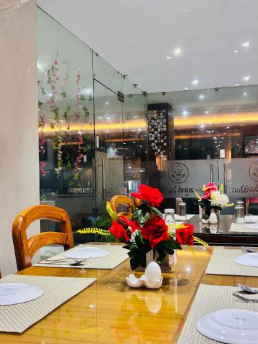 a dining room table with red flowers in a vase at Hotel Kamakhya Inn in Chhatarpur