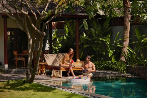 un grupo de personas sentadas junto a una piscina en The Sira, a Luxury Collection Resort and Spa, Lombok, en Tanjung