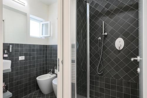 a black tiled bathroom with a shower and a toilet at B&B Quattro Cantoni in Siena