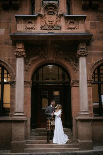 a bride and groom standing in front of a building at AC Hotel by Marriott Glasgow in Glasgow