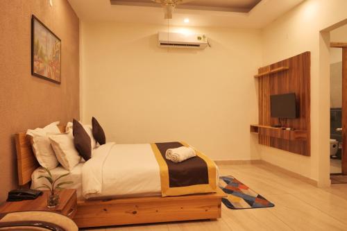 een slaapkamer met een bed en een tv erin bij Kudrat Resort-Jim Corbett in Kota Bāgh