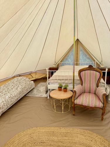 a tent with a bed and a chair and a table at Les Fresses Glamping in Saint-Julien-la-Genète