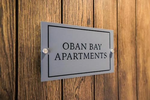 a sign on a wooden wall with the words oban bay experiments at Oban Bay Apartments in Oban