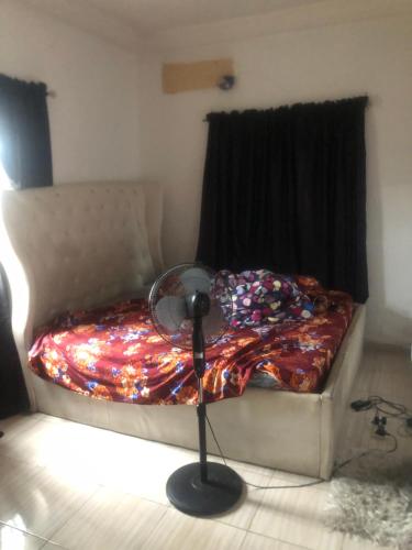 1 dormitorio con 1 cama y ventilador junto a una ventana en Magnificent Cozy Apartment, en Akowonjo