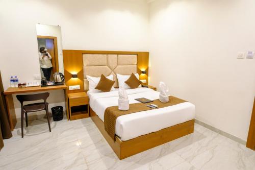 a hotel room with a bed and a woman taking a picture at Hotel Sterling Executive in Navi Mumbai