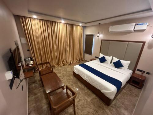 a bedroom with a bed and a chair and a television at AuroBESHA in Puducherry Airpoert