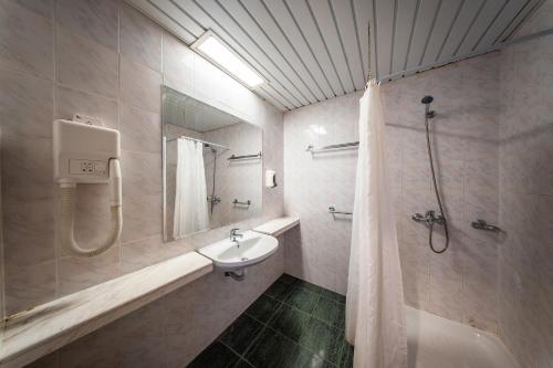 a white bathroom with a sink and a shower at Hotel Zdravets in Varna City
