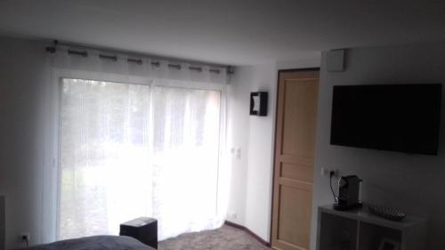 a bedroom with a large window and a television at La Gentilhommière - Chambre avec sauna et jaccuzzi in Saint-Roch