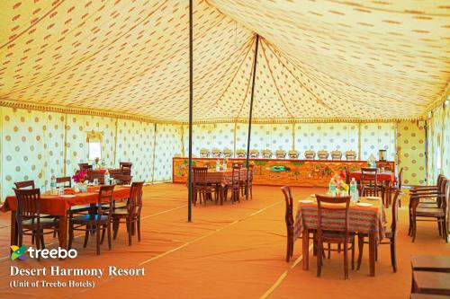 a dining room with tables and chairs in a tent at Treebo Desert Harmony Camp in Sām