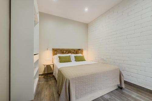 a white bedroom with a bed and a white brick wall at Novus Homes Barcelona Santa Eulalia in Hospitalet de Llobregat