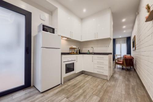 a kitchen with white cabinets and a white refrigerator at Novus Homes Barcelona Santa Eulalia in Hospitalet de Llobregat