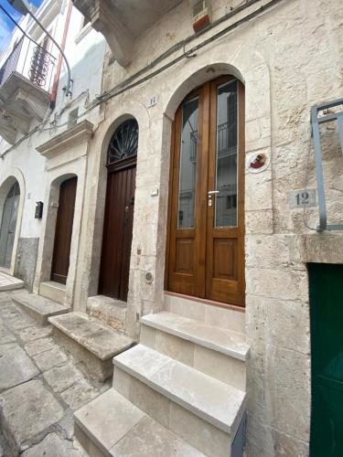 a stone building with a wooden door and stairs at La Casa della Pizzica in Ostuni