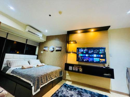 Un dormitorio con una cama y un televisor de pantalla plana. en Poblacion Stay with Pool Gym Jacuzzi and Pool Table, en Manila