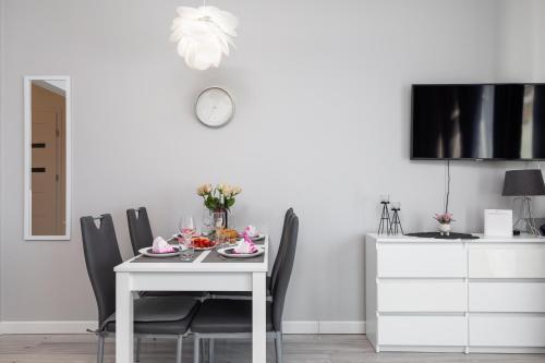 a dining room table with chairs and a clock on the wall at Paraiso Nadmorskie Apartamenty z Basenem i Parkingiem by Noclegi Renters in Łukęcin