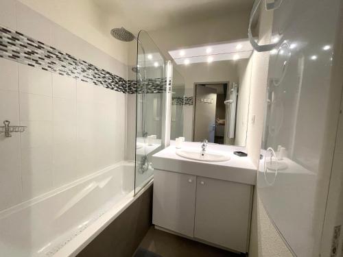une salle de bain blanche avec un lavabo et une douche dans l'établissement Appartement 35 m2 4p avec piscine chauffée la foux d Allos, à La Foux d'Allos