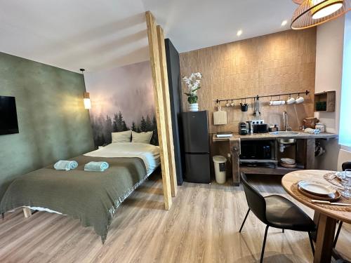 a bedroom with a bed and a table and a kitchen at Craft Home - Le menuisier - Balneo - Parking privé in Saint-Étienne