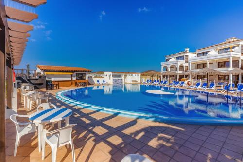 a swimming pool with chairs and umbrellas at a resort at Pebble Beach in San Miguel de Abona