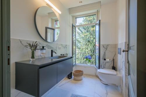 a bathroom with a sink and a toilet and a mirror at Villa Spa Dalia in Cannobio