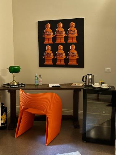 an orange chair sitting in front of a table with a picture at Ginevra Boutique Rooms - Palazzo Leosini - Residenze D'Epoca in LʼAquila