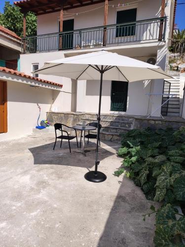 a table and chairs under an umbrella in front of a house at Trikeri pleasant stay in Ayía Kiriakí
