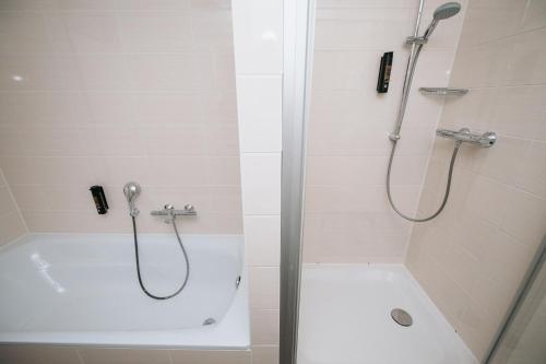 a bathroom with a shower and a bath tub with a shower at Coffee Fellows Hotel München-Freiham in Munich