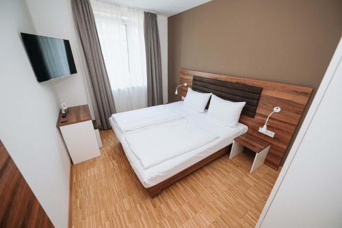 a small bedroom with a white bed and a television at Coffee Fellows Hotel München-Freiham in Munich