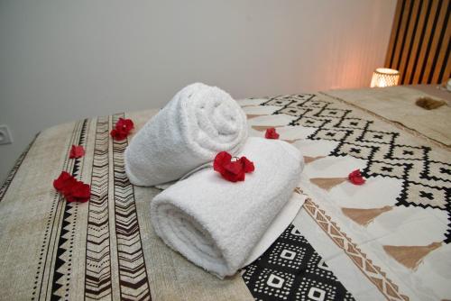 a pair of towels on a bed with red flowers at O'Meublés des 2Bois- Le Filao-Piscine chauffée & Spa in Le Tampon