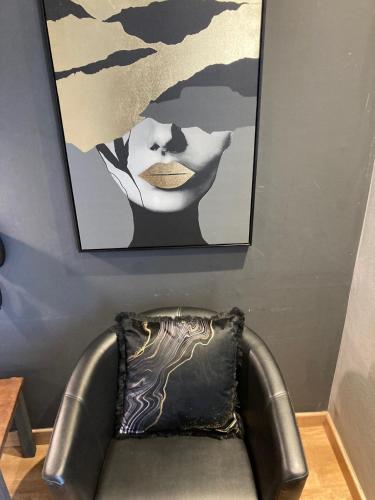 a leather chair sitting under a painting on a wall at Hôtel Des Argousiers in Ambleteuse