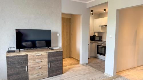 Una sala de estar con un televisor de pantalla plana sobre un mueble de madera. en Piaskowa Stay by LibertaRent, en Wałbrzych