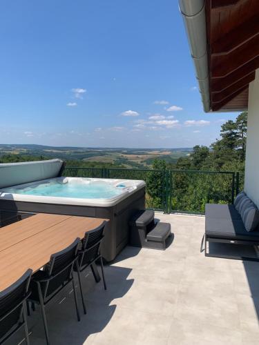 a patio with a hot tub and tables and chairs at Bakonyi Panoráma Élményház in Tés