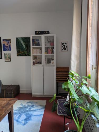 un salon avec une armoire blanche et une plante dans l'établissement 2 pieces avec clim - au pied du Panthéon, à Paris