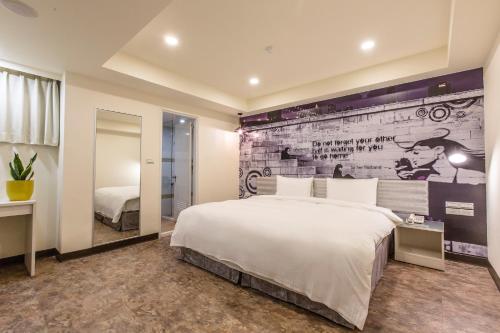 a bedroom with a large white bed and a wall at The Cloud Hotel Zhongli Branch in Zhongli