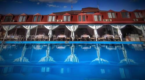a pool in front of a hotel with tables and chairs at Hotel Racic Self-Check In in Voyvodinovo