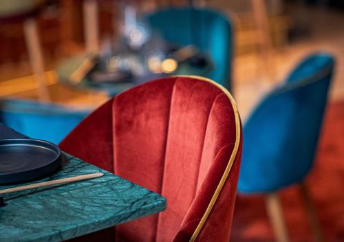 a red chair sitting in front of a table at Montebelo Vista Alegre Lisboa Chiado Hotel in Lisbon