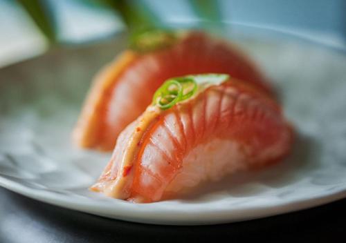 two pieces of salmon sitting on a white plate at Montebelo Vista Alegre Lisboa Chiado Hotel in Lisbon