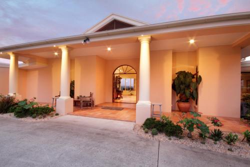 a home with a porch with columns and a plant at River Rock Retreat in Maroochy River