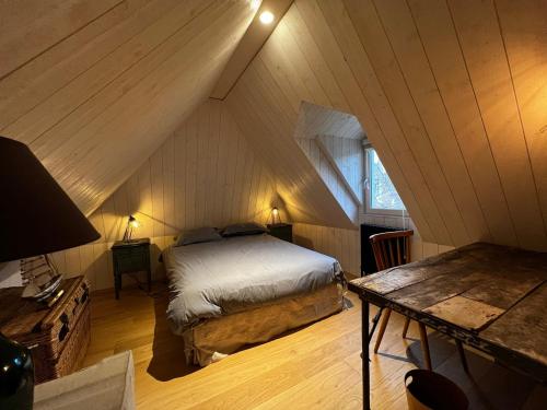 - une chambre mansardée avec un lit et une table dans l'établissement Chaleureuse ferme restaurée au calme avec piscine, à Fiquefleur-Équainville
