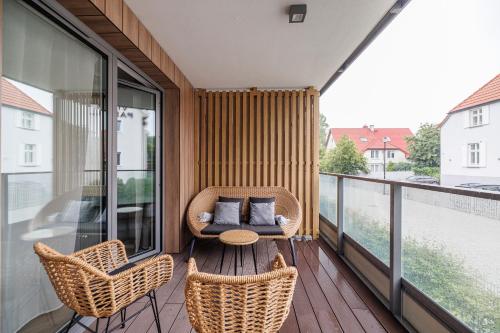 a balcony with wicker chairs and a table at Rezydencja Merwede Aparthotel - My Rest in Gdańsk