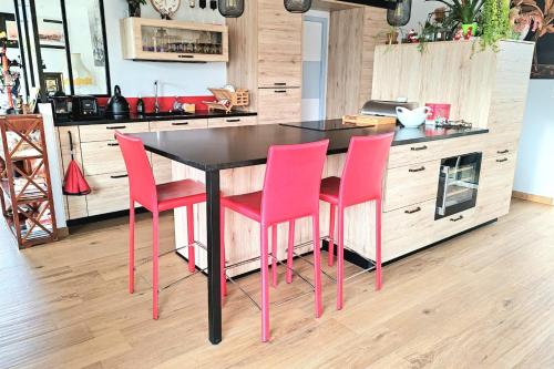 une cuisine avec une table noire et des chaises roses dans l'établissement Spacious house with garden near the beach, à Saint-Malo