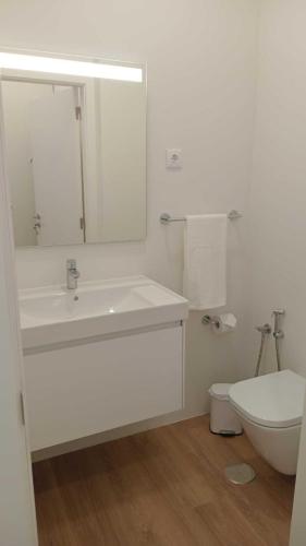 a white bathroom with a sink and a toilet at Apartamento Sonho Sky in Ponta Delgada