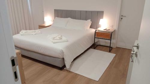 ein Schlafzimmer mit einem großen weißen Bett mit zwei Nachttischen in der Unterkunft Apartamento Sonho Sky in Ponta Delgada