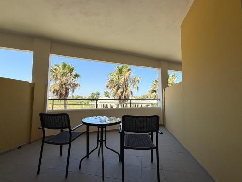 a balcony with a table and chairs and palm trees at Kos Palace in Tigaki